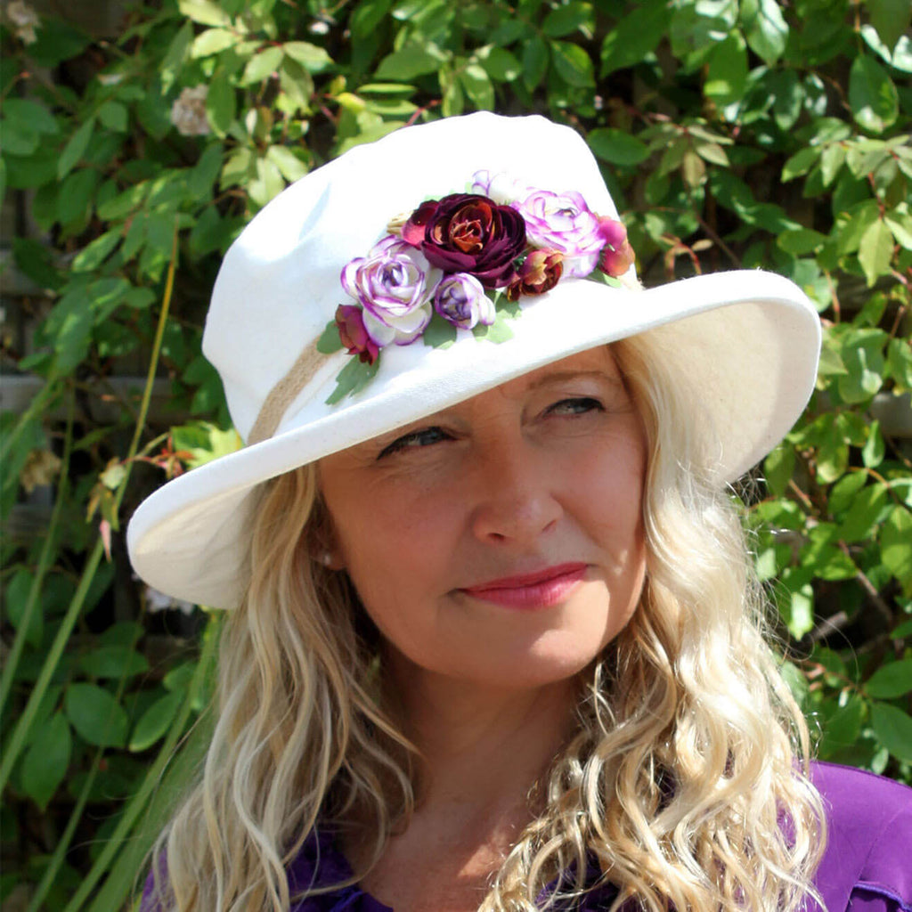 ladies cream sun hat with purple mix flowers on crown of hat on lady